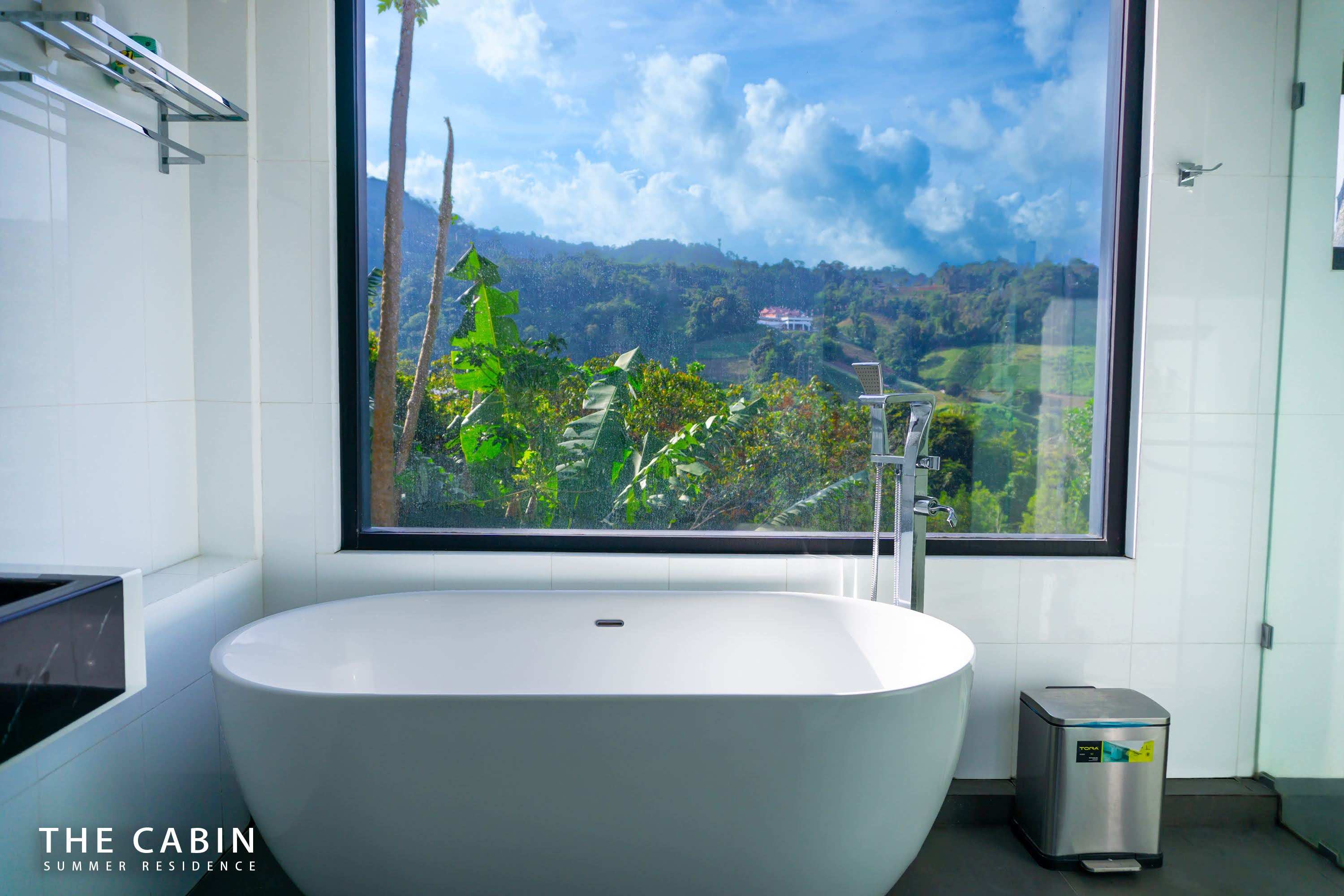 Room 1 ensuite with the tub set against the window, pool and valley in view.