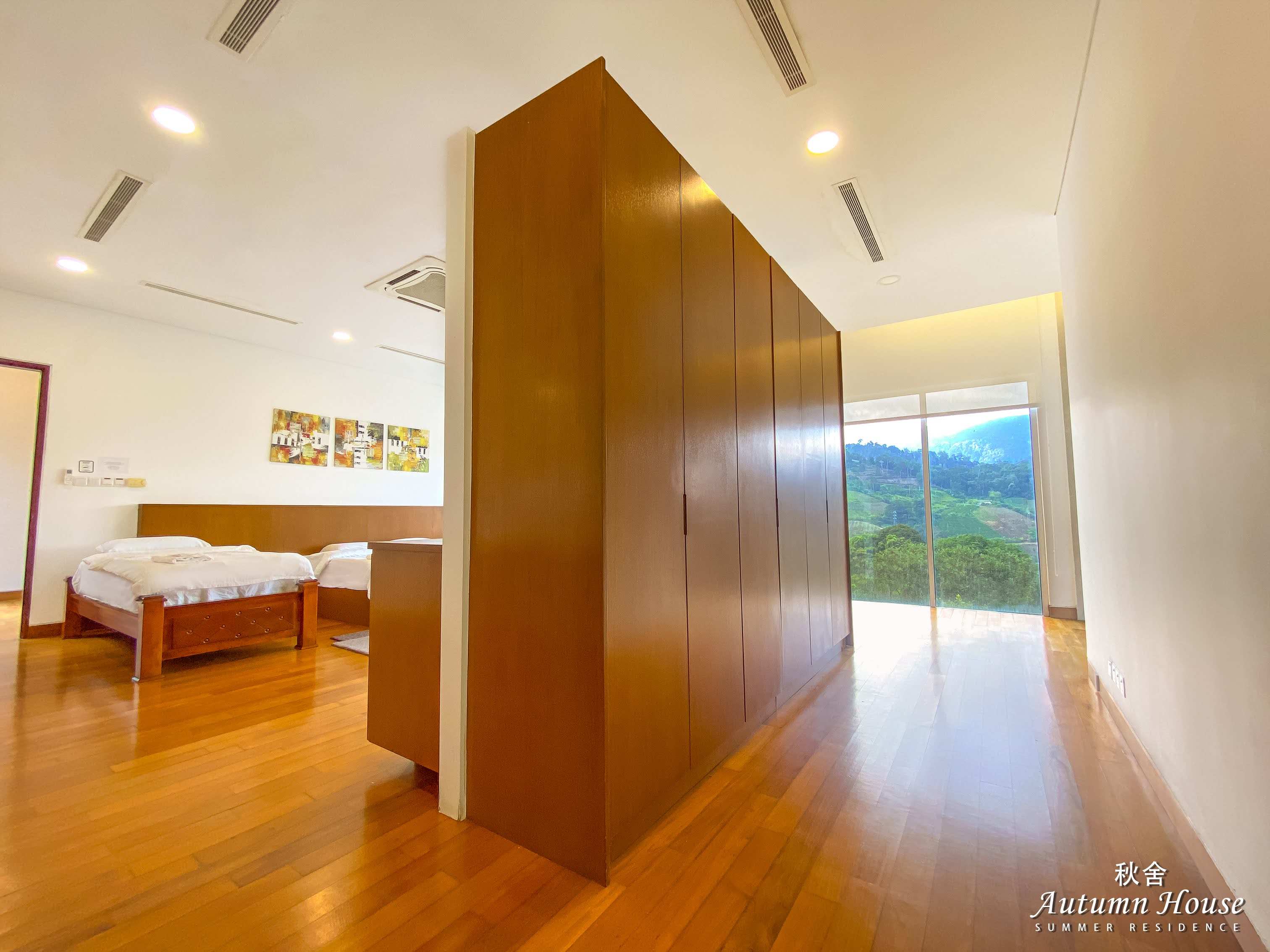 Bedroom five with its timber-panelled walk-in wardrobe divider and a glass door to the view.