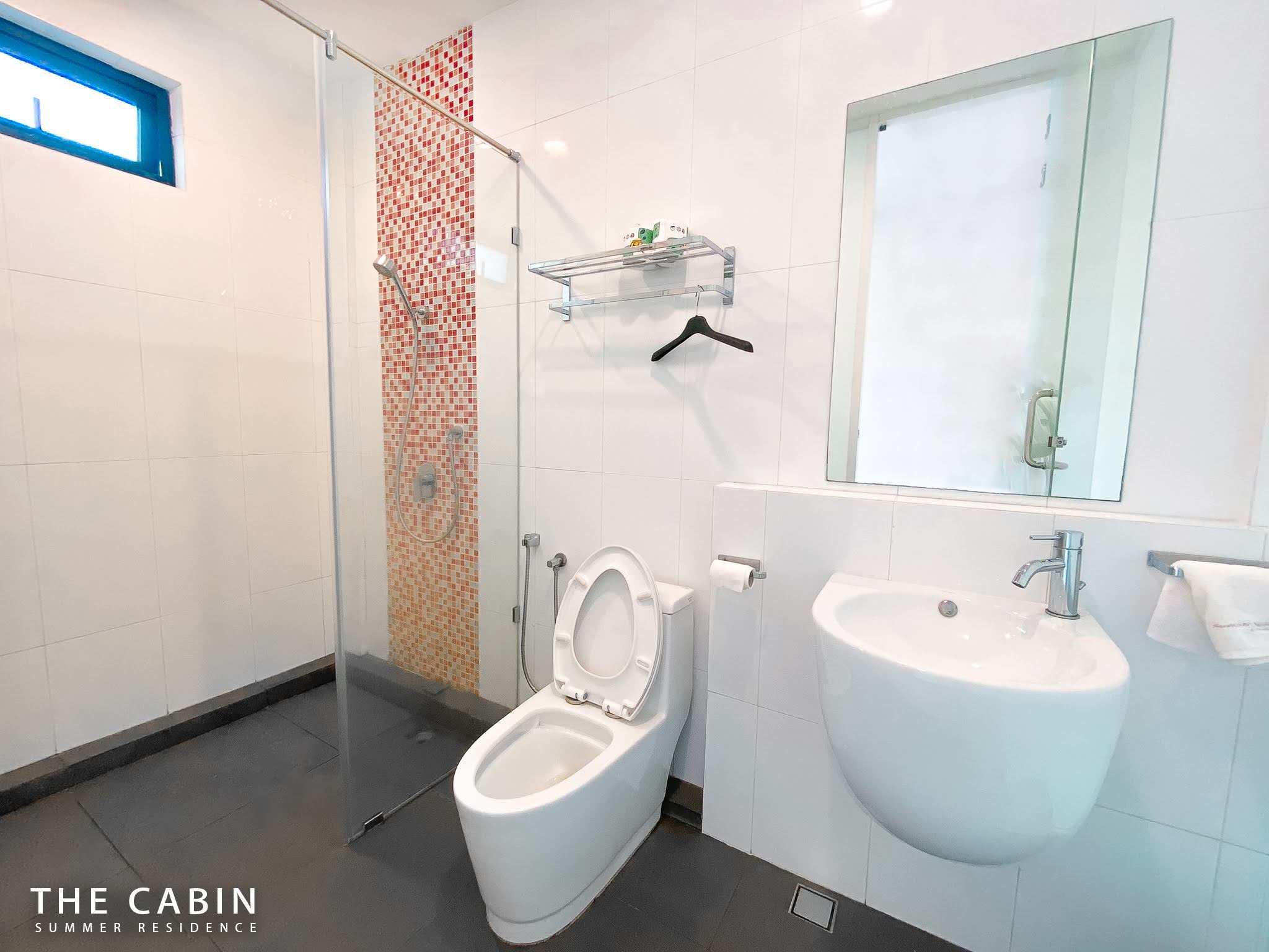 Room 2 ensuite: glass-walled shower with red and orange mosaic accent tile, toilet and wall-hung sink.