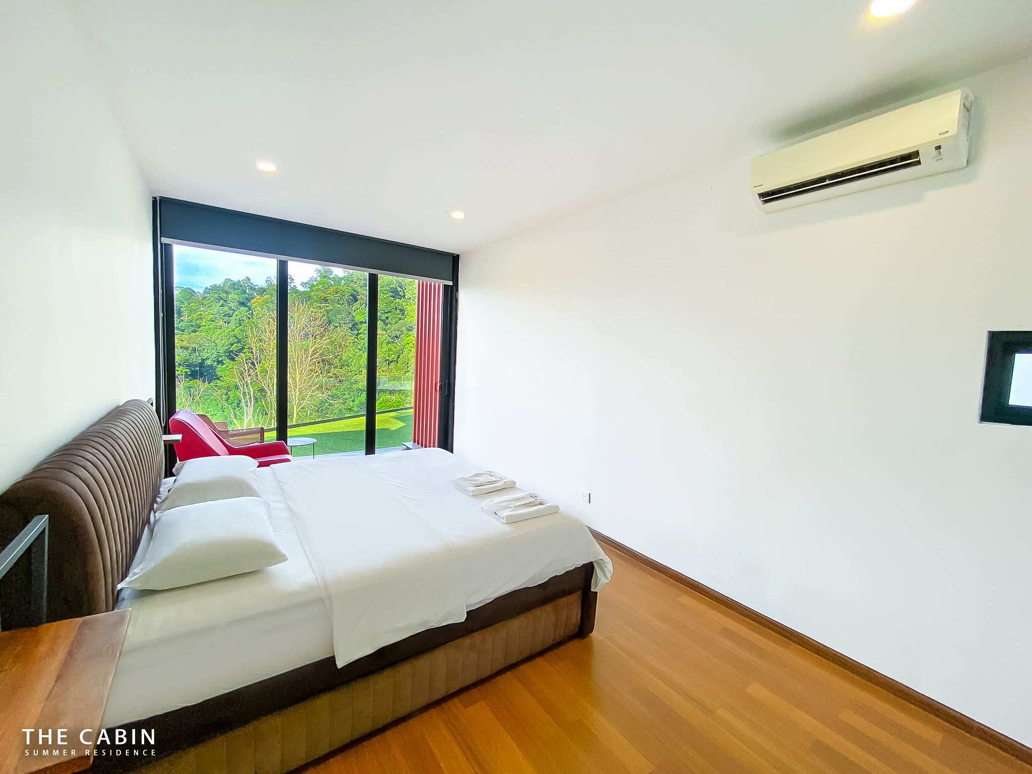 Room 2 with its balcony beyond the glass doors, a red armchair outside and mountains behind.