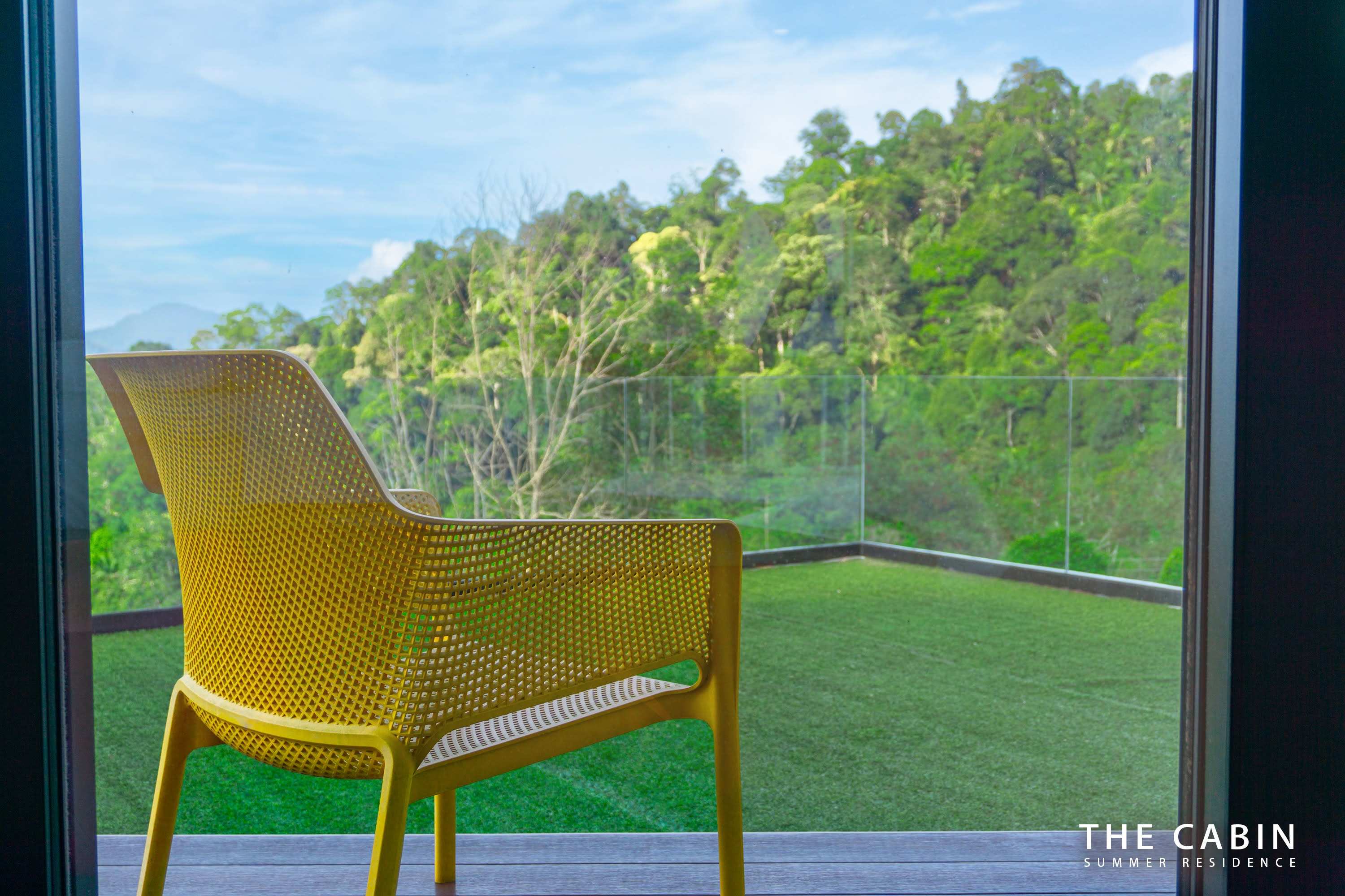 A yellow perforated chair on the Room 3 balcony, jungle canopy and mountains beyond.
