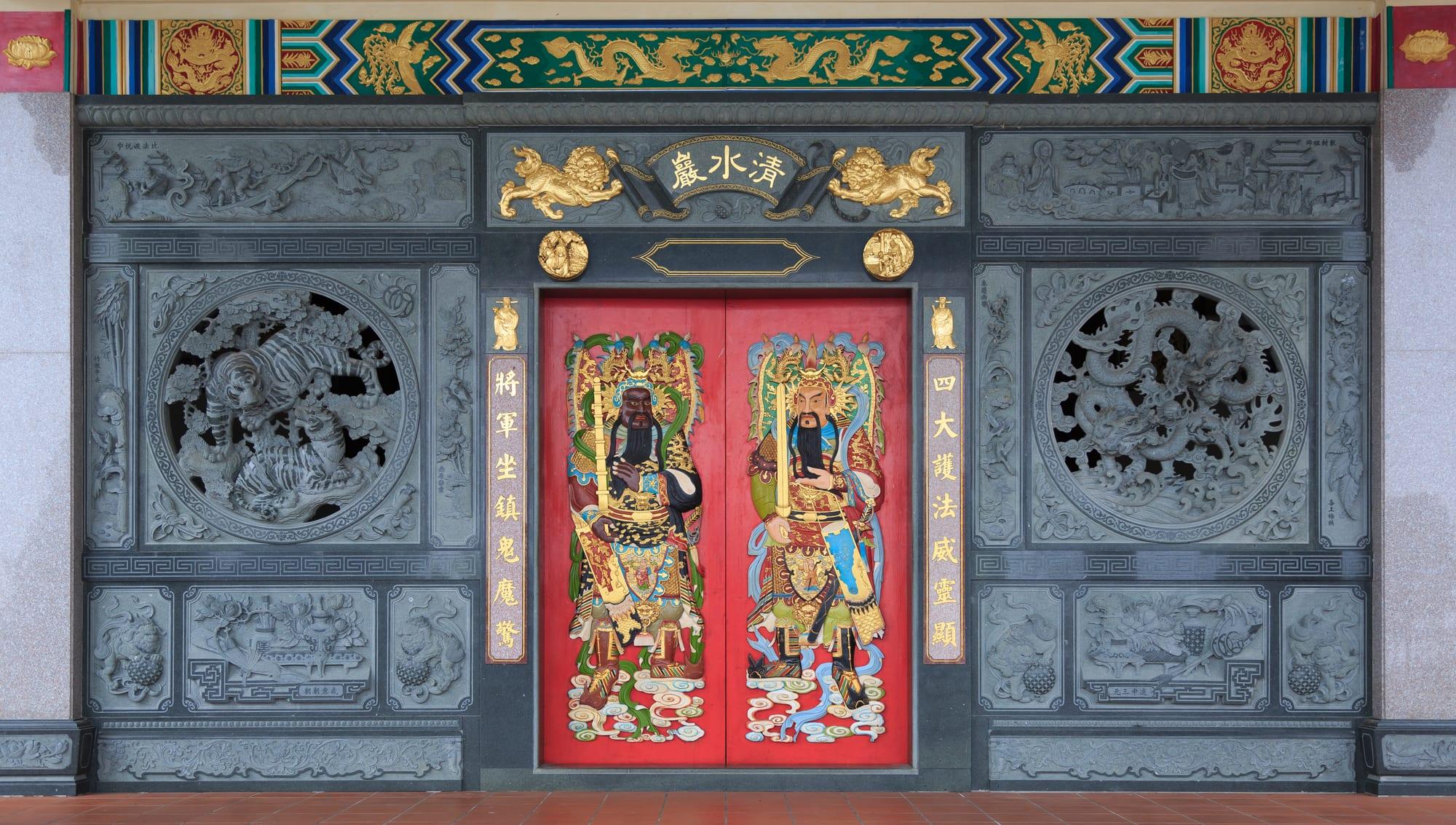 The carved stone panels and painted door gods at the entrance of Chin Swee Caves Temple