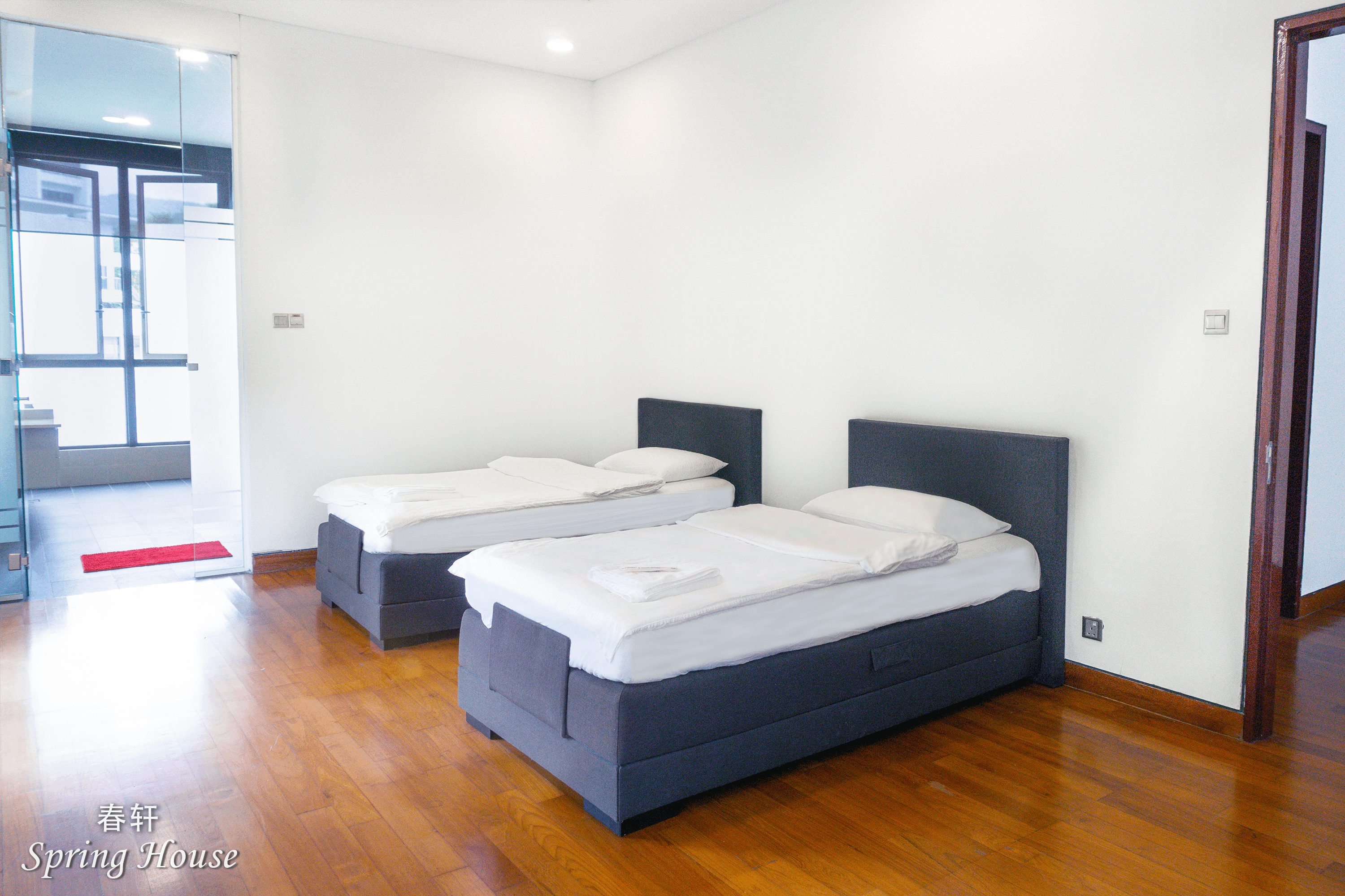 Twin room with two grey upholstered beds, a mirrored wardrobe and a glass ensuite door.
