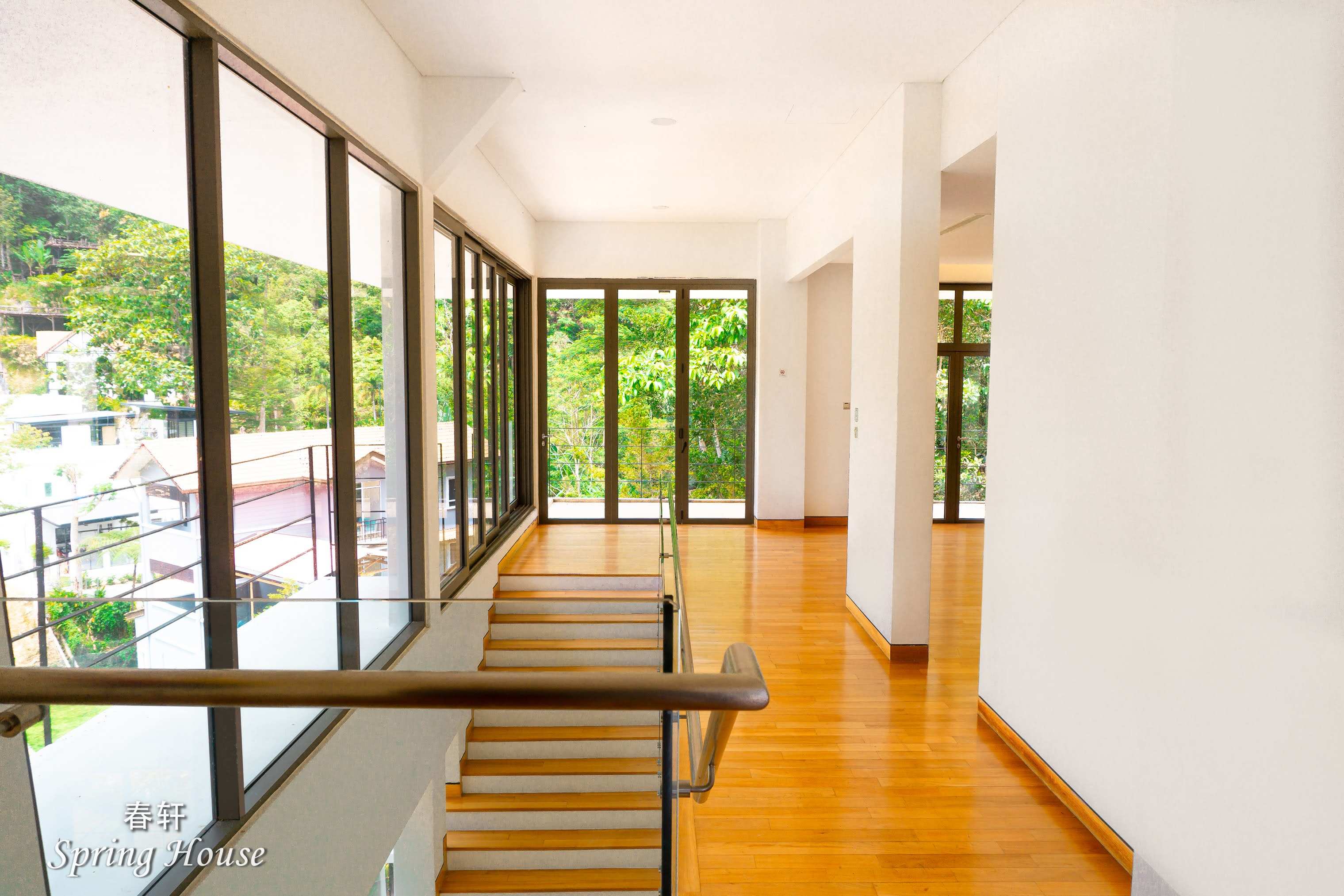 The same upper-floor corridor from the far end, mountain views through the window wall.
