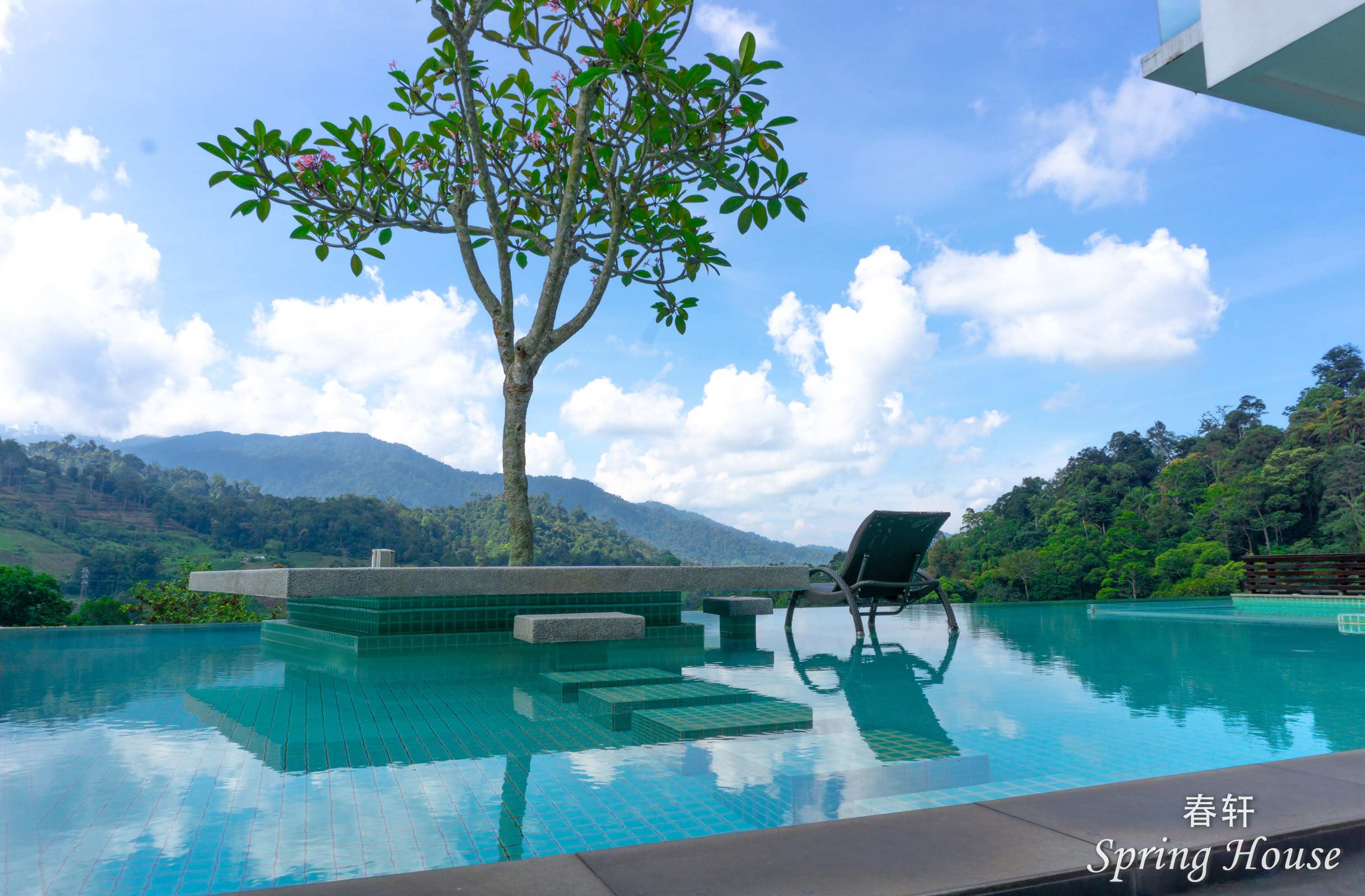 The pool planter island and lounge chair under a blue sky, mountains behind.