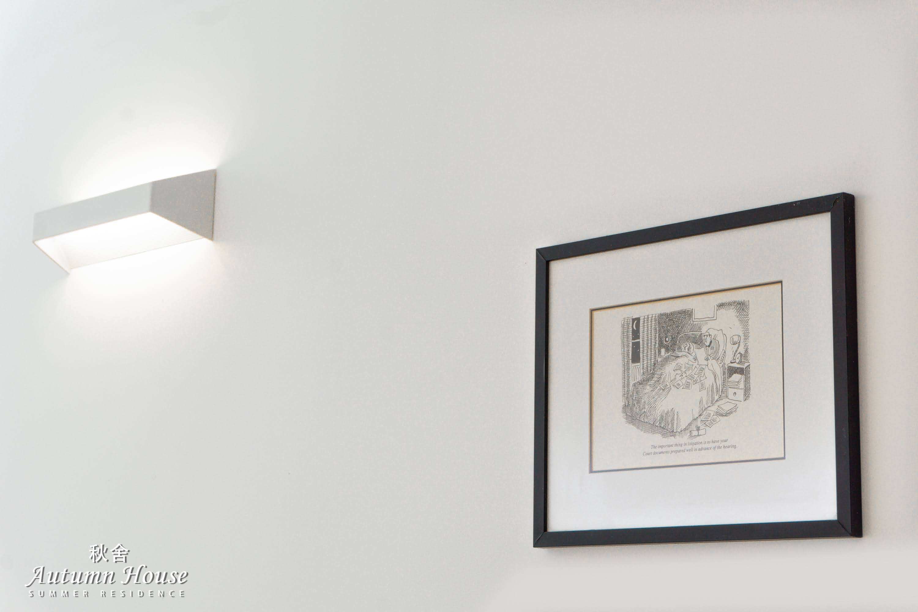 Wall sconce and a small framed print on a plain wall.