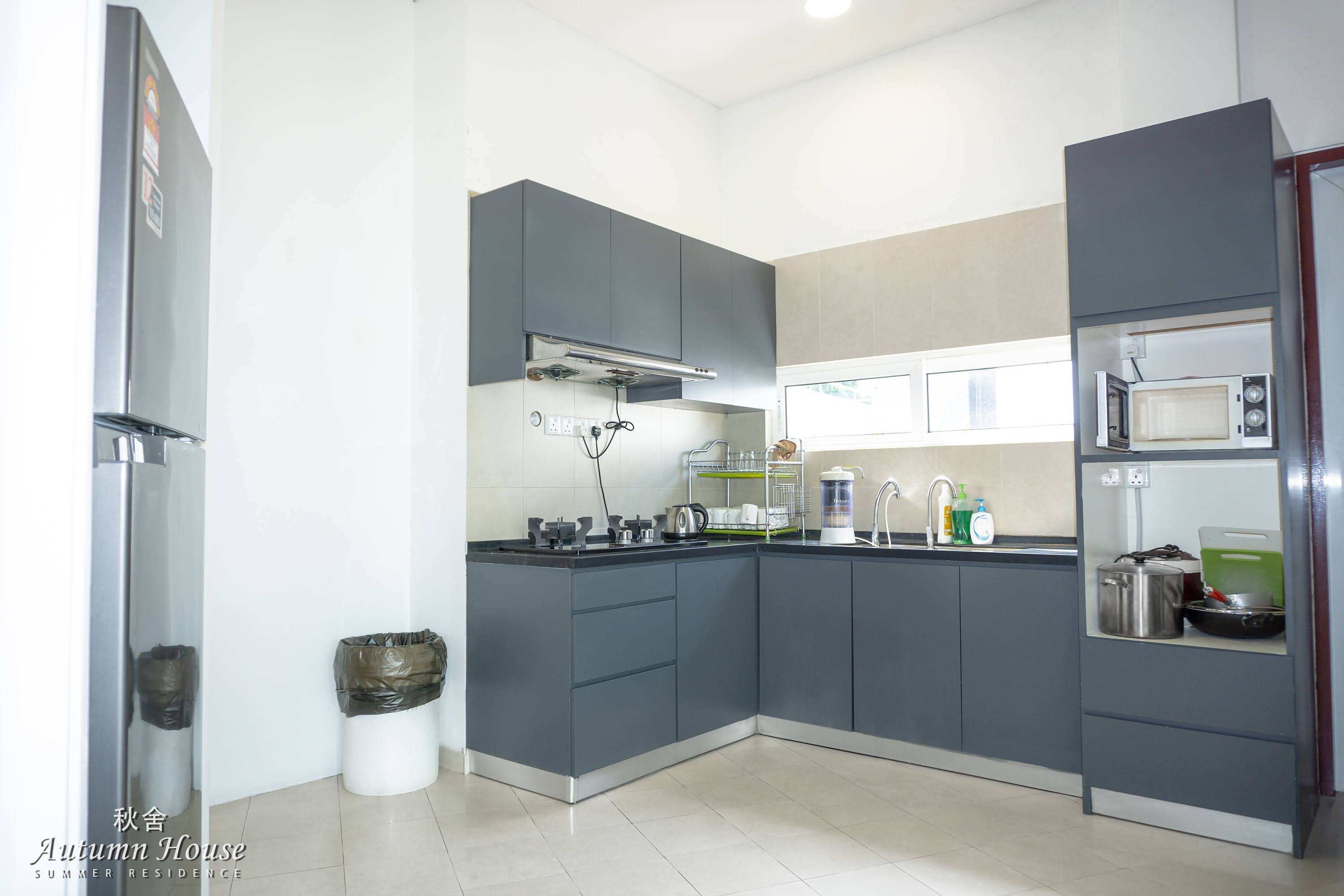 Wet-style kitchen with dark grey cabinetry, gas hob, dish rack, microwave and water filter.