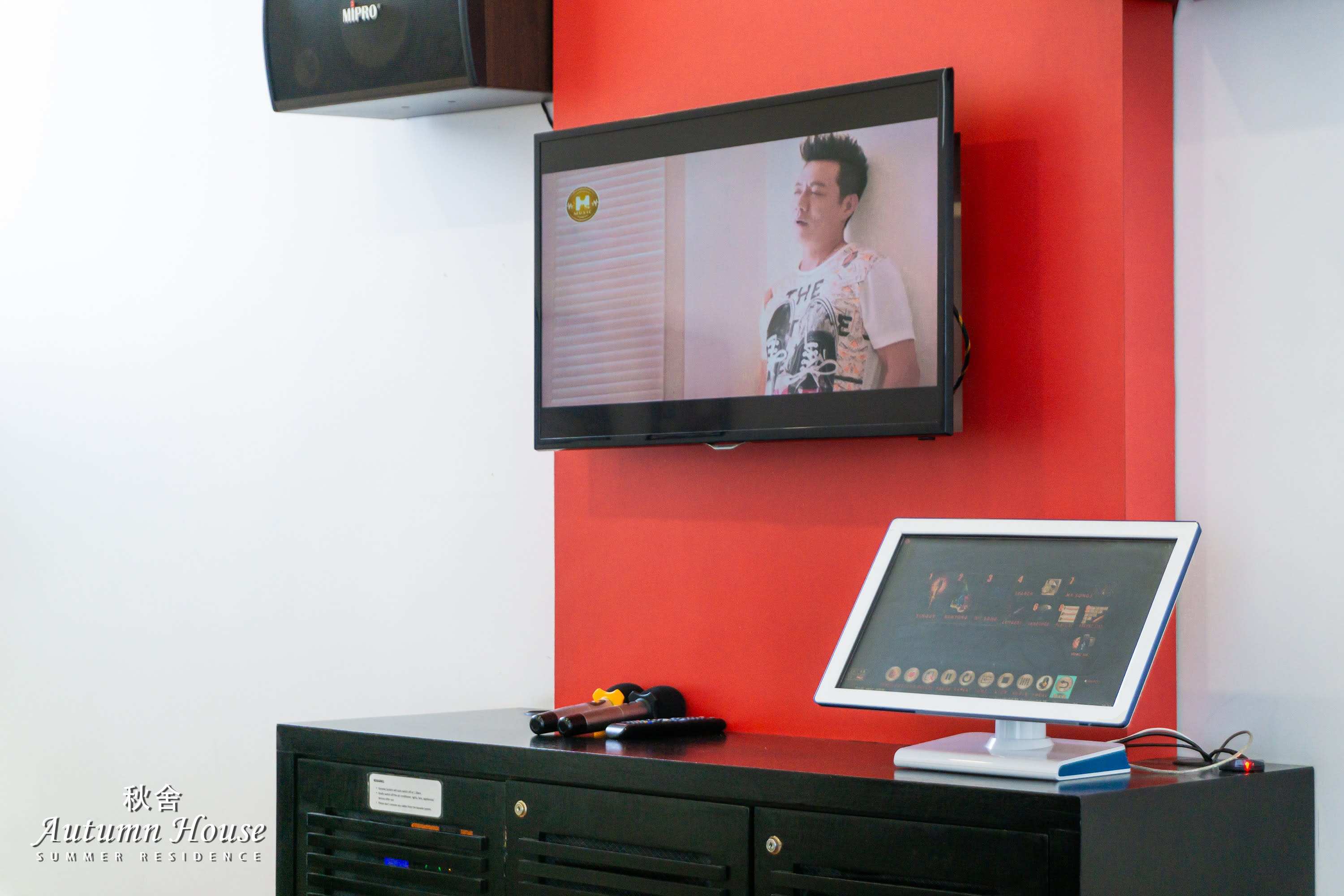 Close-up of the karaoke screen and touchscreen song selector with microphones on the credenza.
