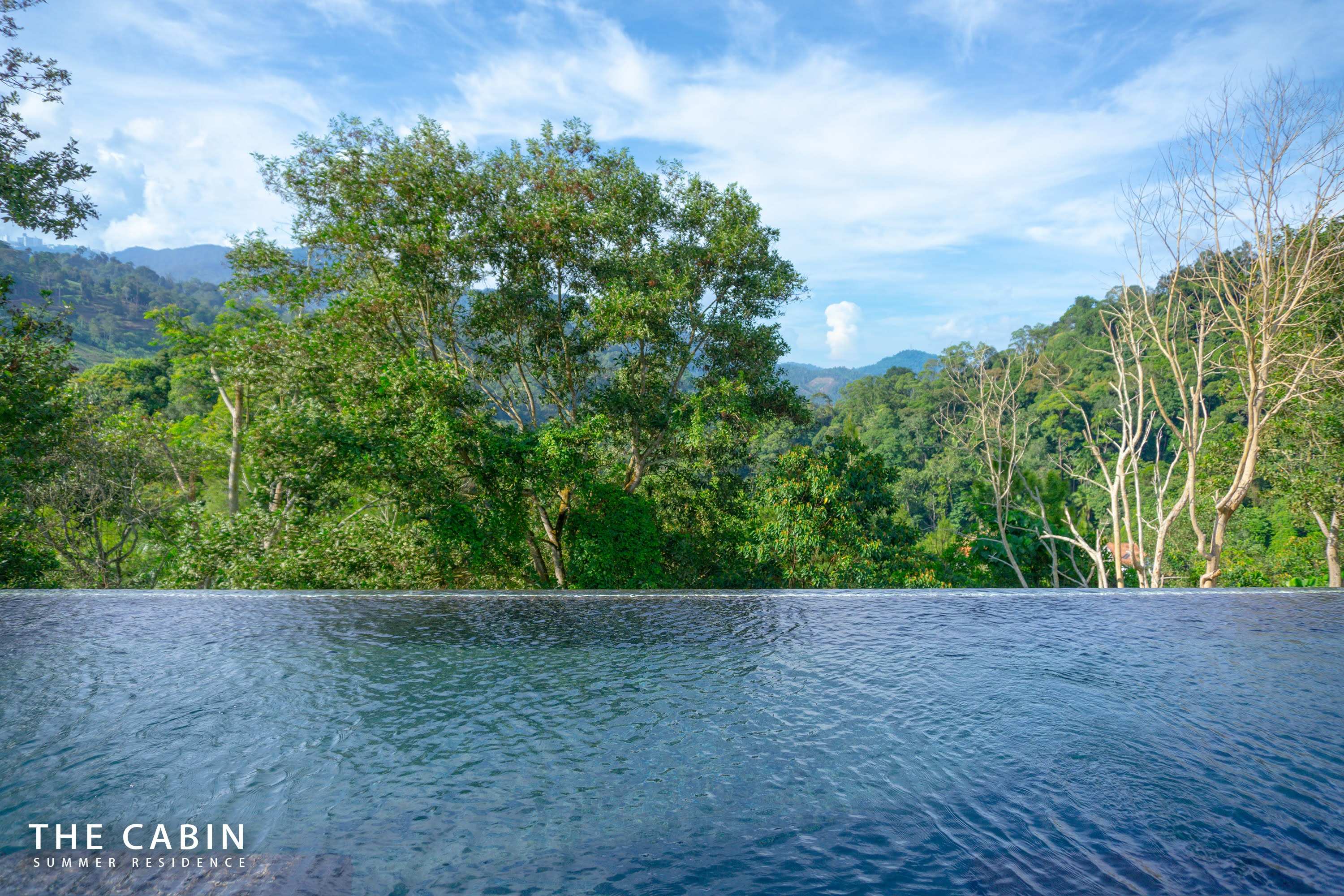 Water-level view across the infinity edge to layered forest and mountains.