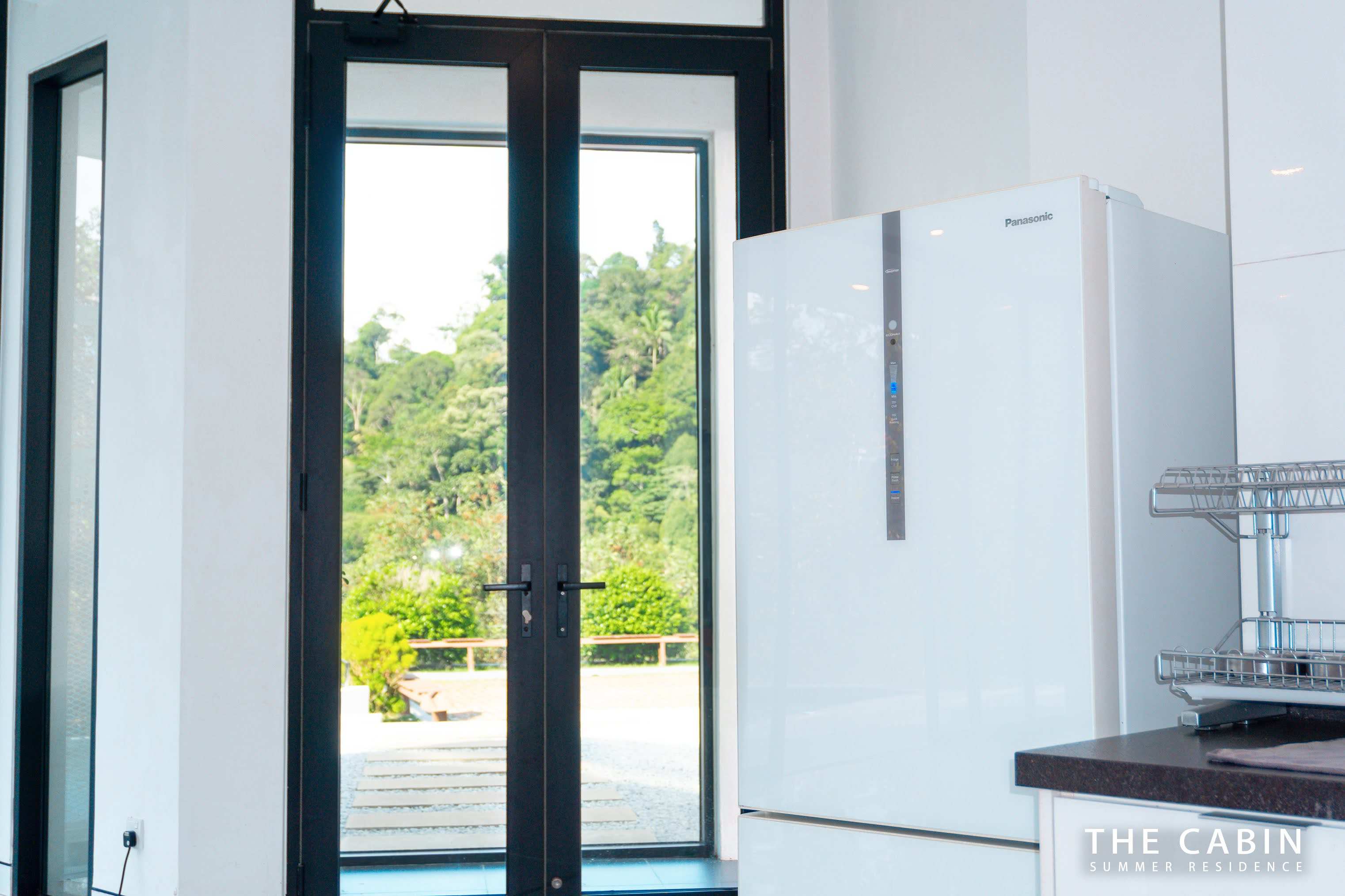 A second fridge beside the glass double doors leading outside.