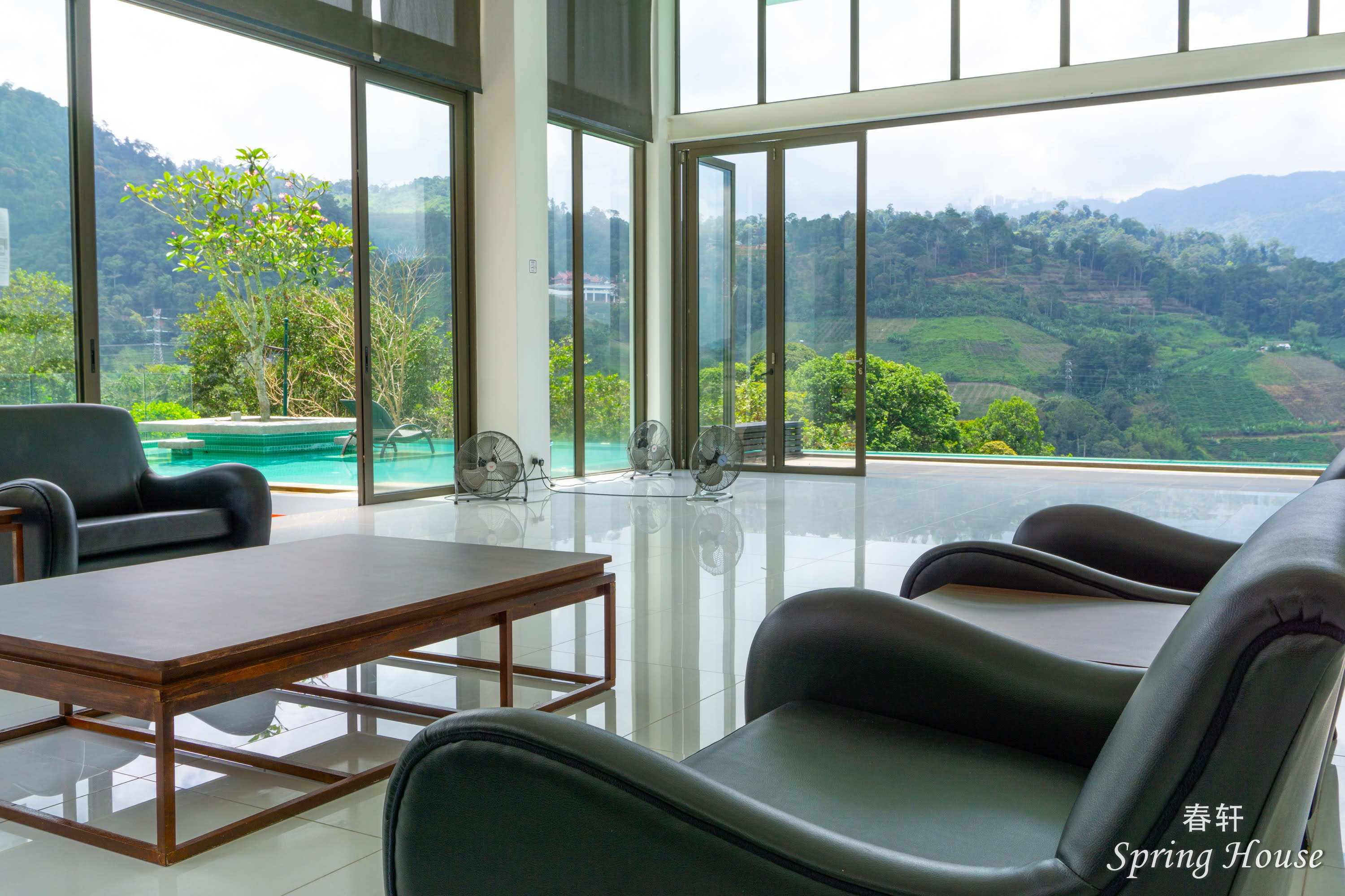 Lounge seating beside the glass wall, with the pool and mountain view behind.