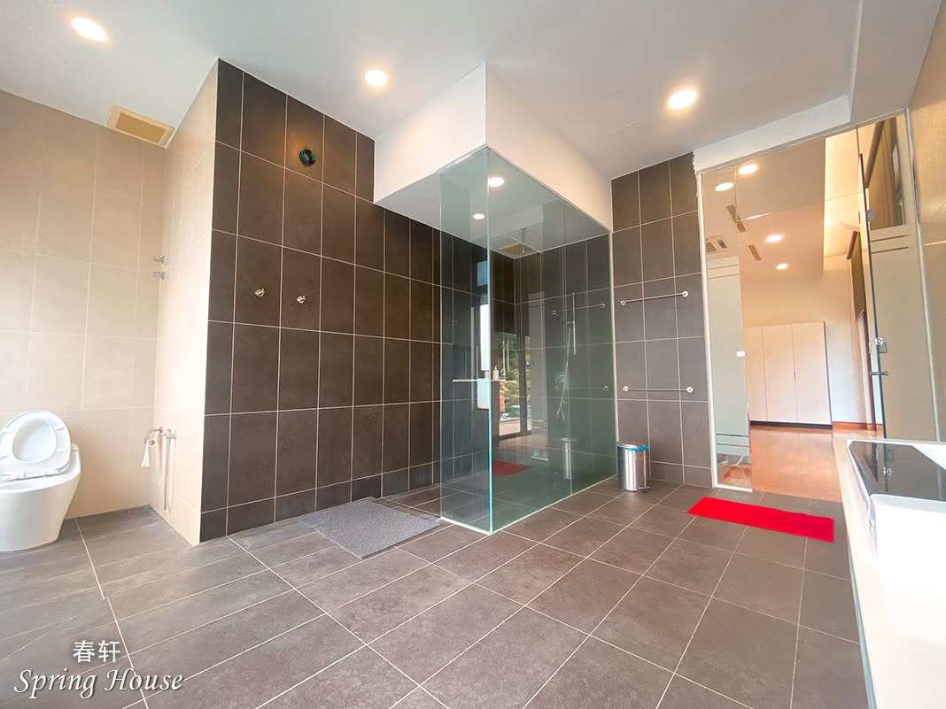 Large ensuite with a walk-in glass shower, double vanity and dark tiled walls.
