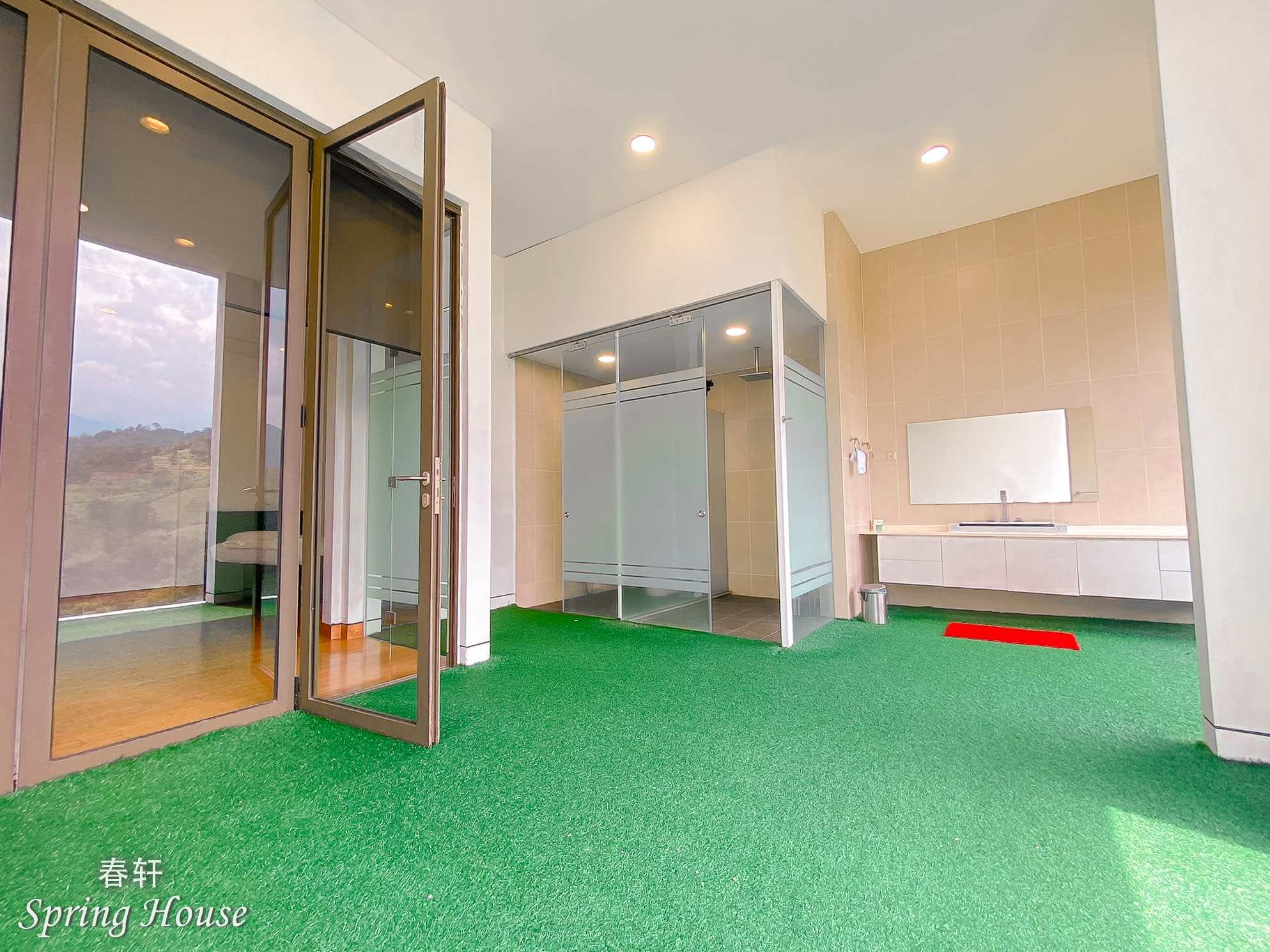 Beige-tiled bathroom with a frosted-glass shower cubicle, vanity and a mountain-view window.