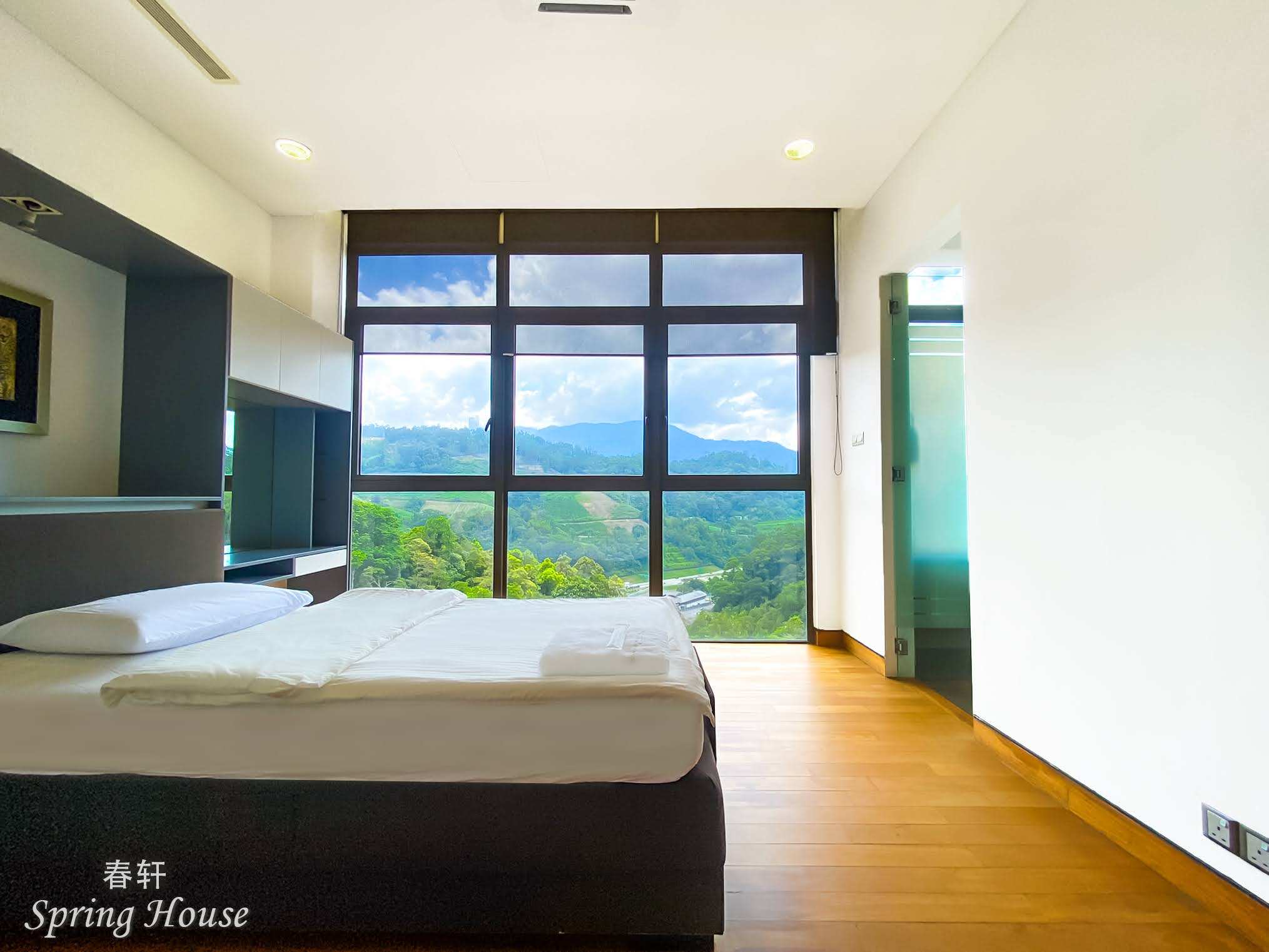Bedroom with a dark bed, wall display shelf and full-height mountain-view windows beside the ensuite door.