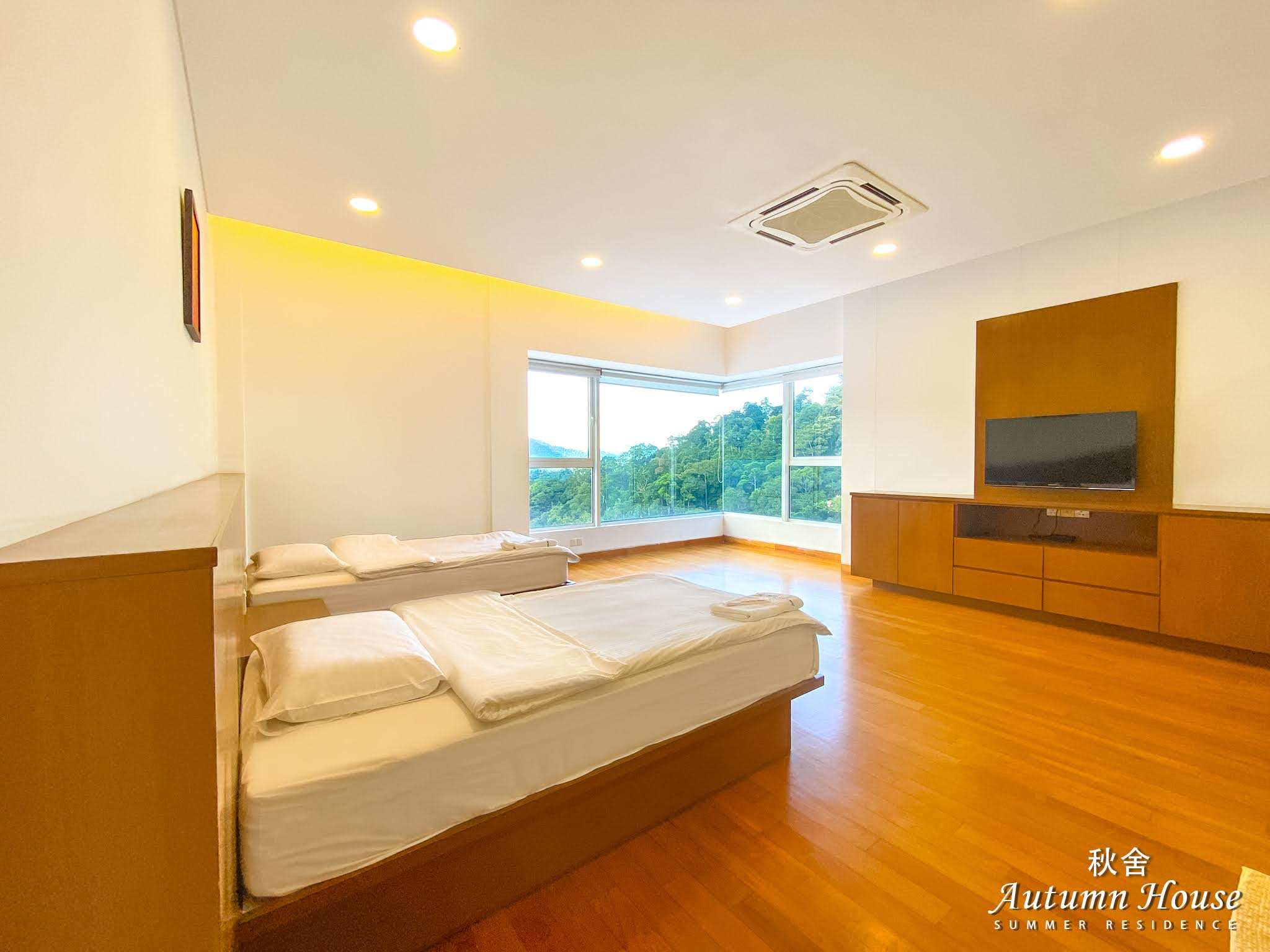 Twin room with two single beds, a wall-mounted TV and a corner window onto the forest.