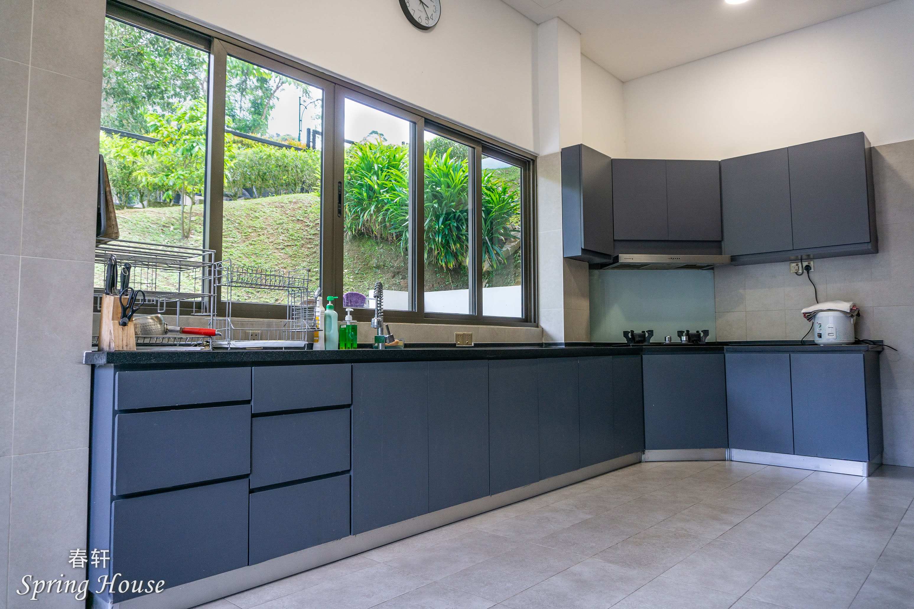 Full L-shaped kitchen: fridge, rice cooker and water urn on the counter, tiled floor.