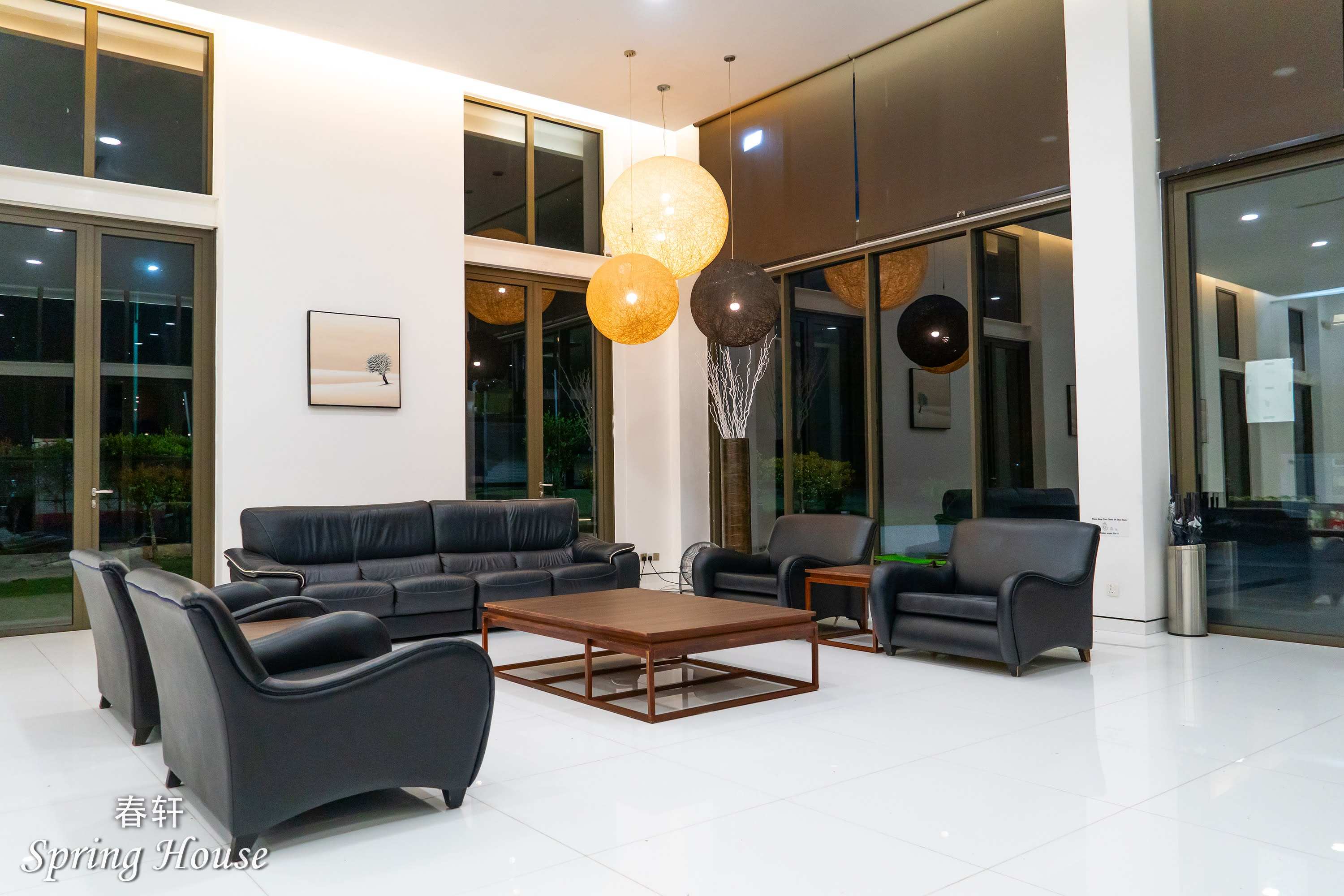 The living hall at night, warm ambient light and glowing rattan pendant orbs.