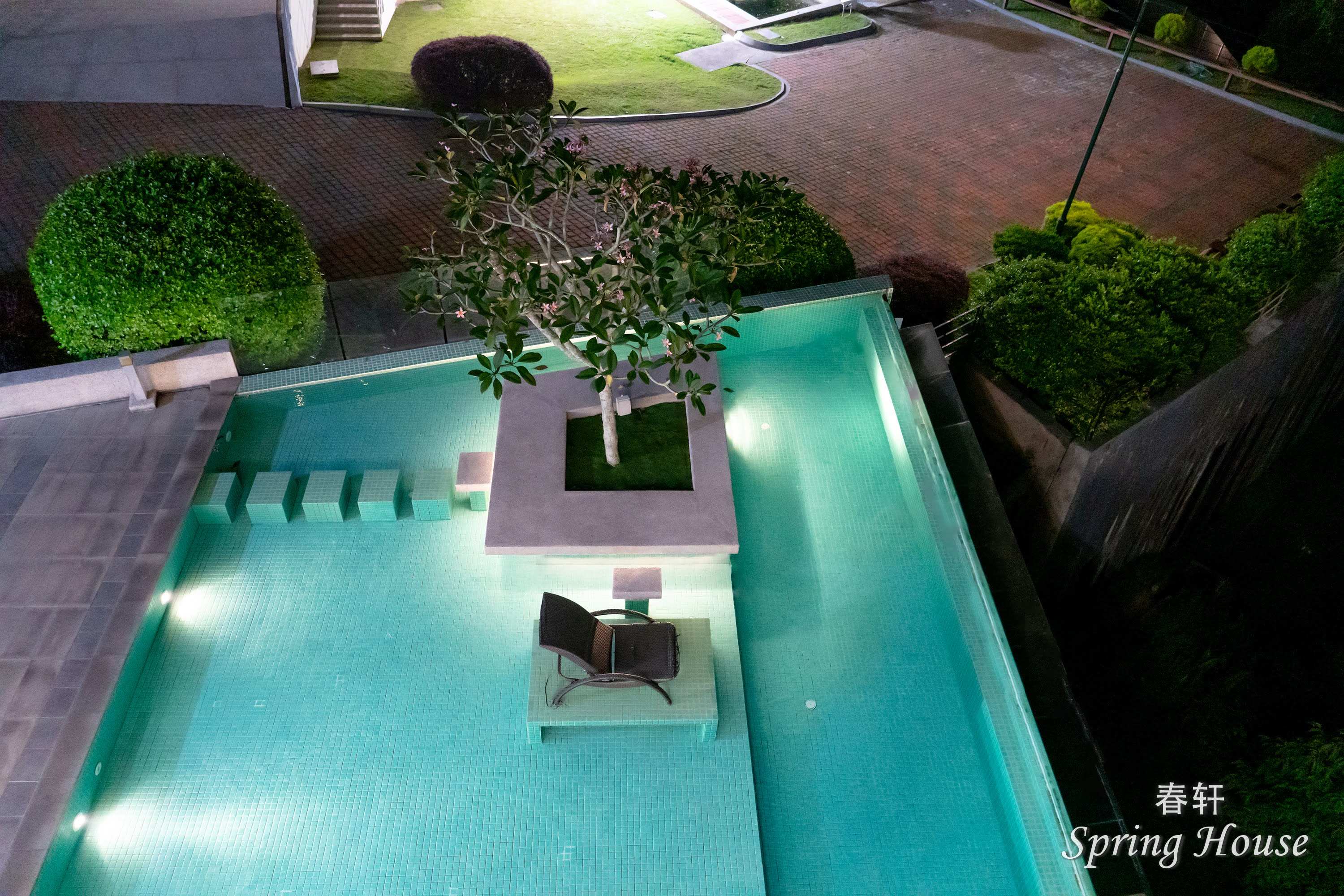 Elevated night view of the pool feature with the garden path and lawn beyond.