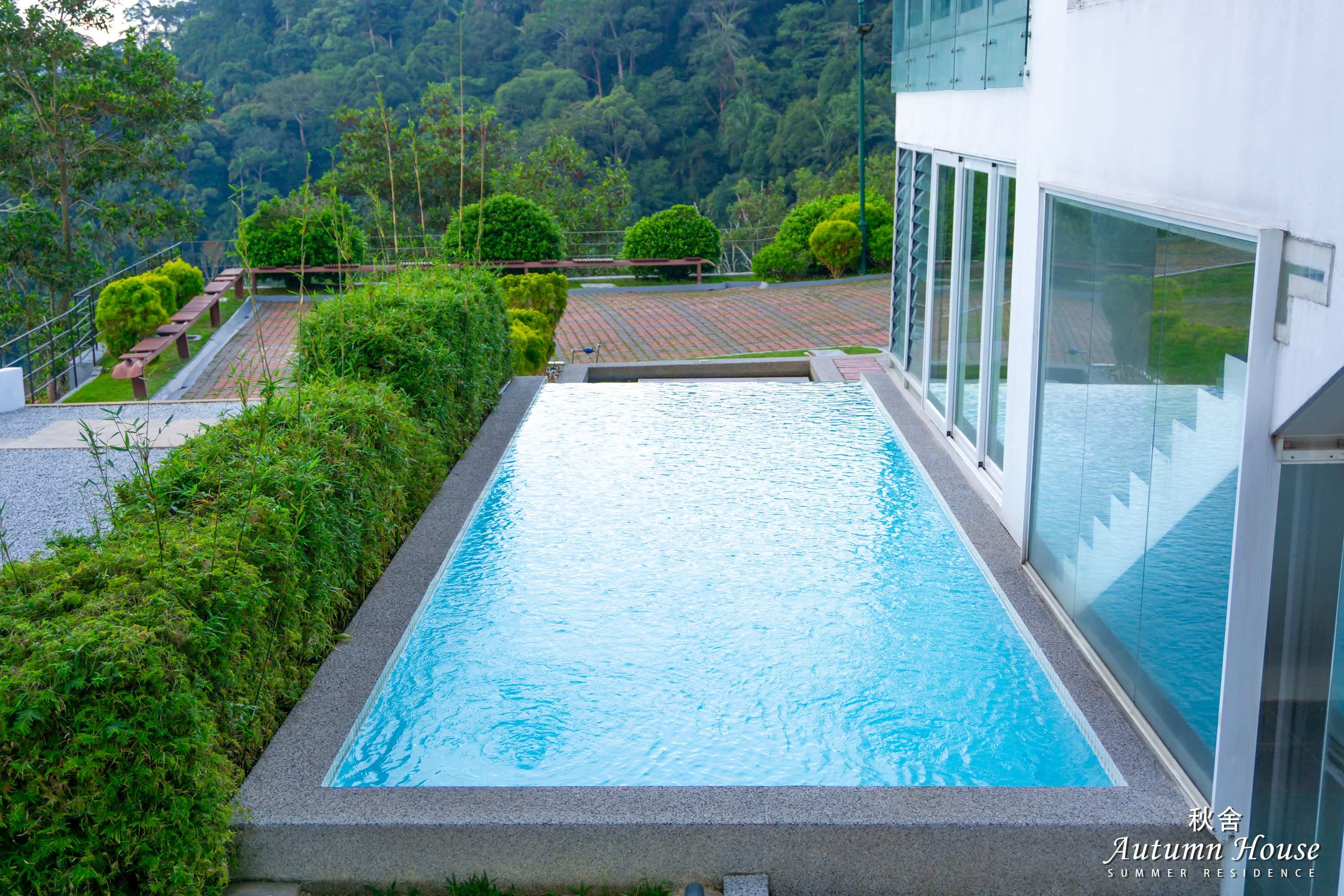 The infinity-edge pool running alongside the house, with the jungle hillside behind.