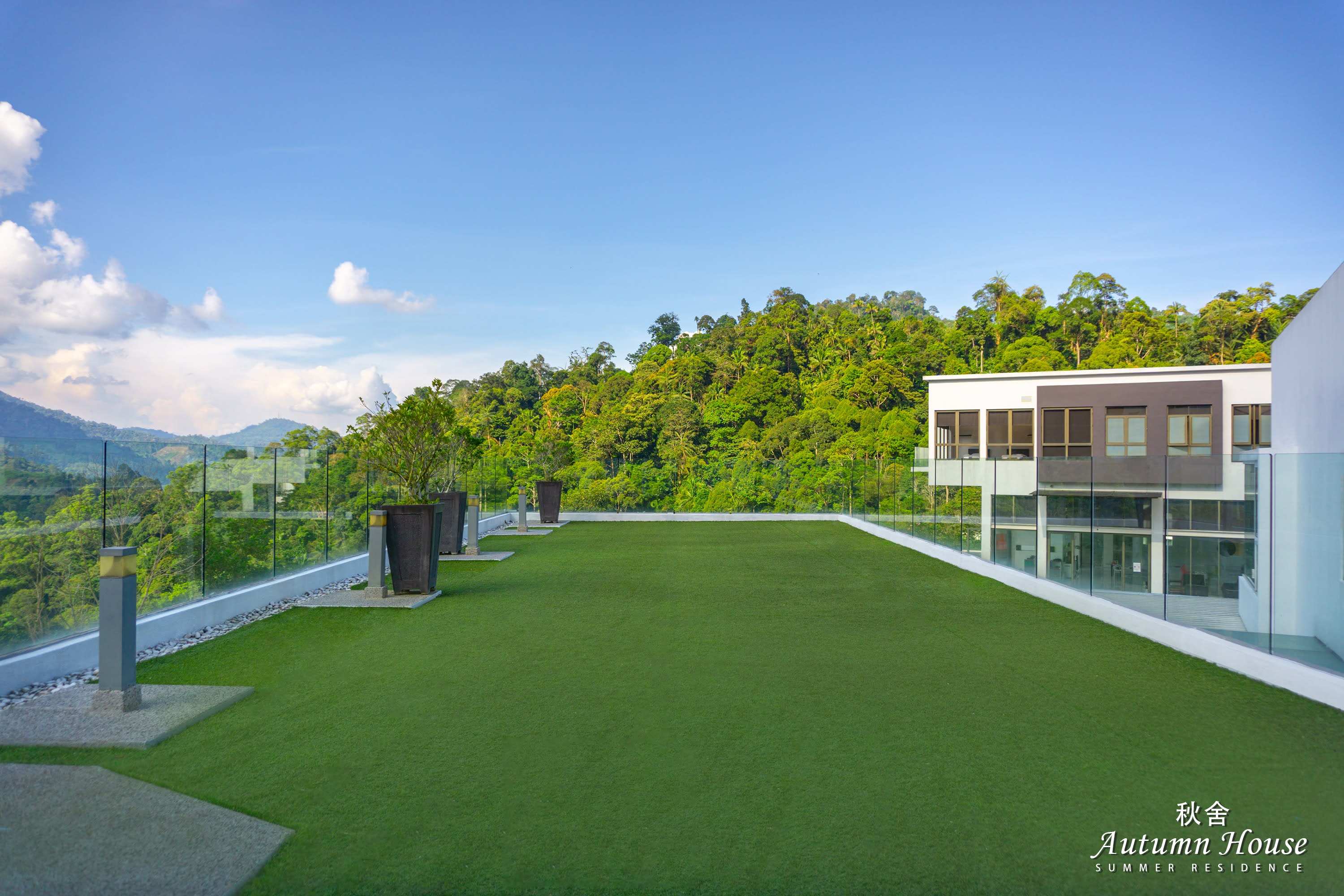 Rooftop garden with artificial turf, glass balustrade and potted plants, forested hills all around.