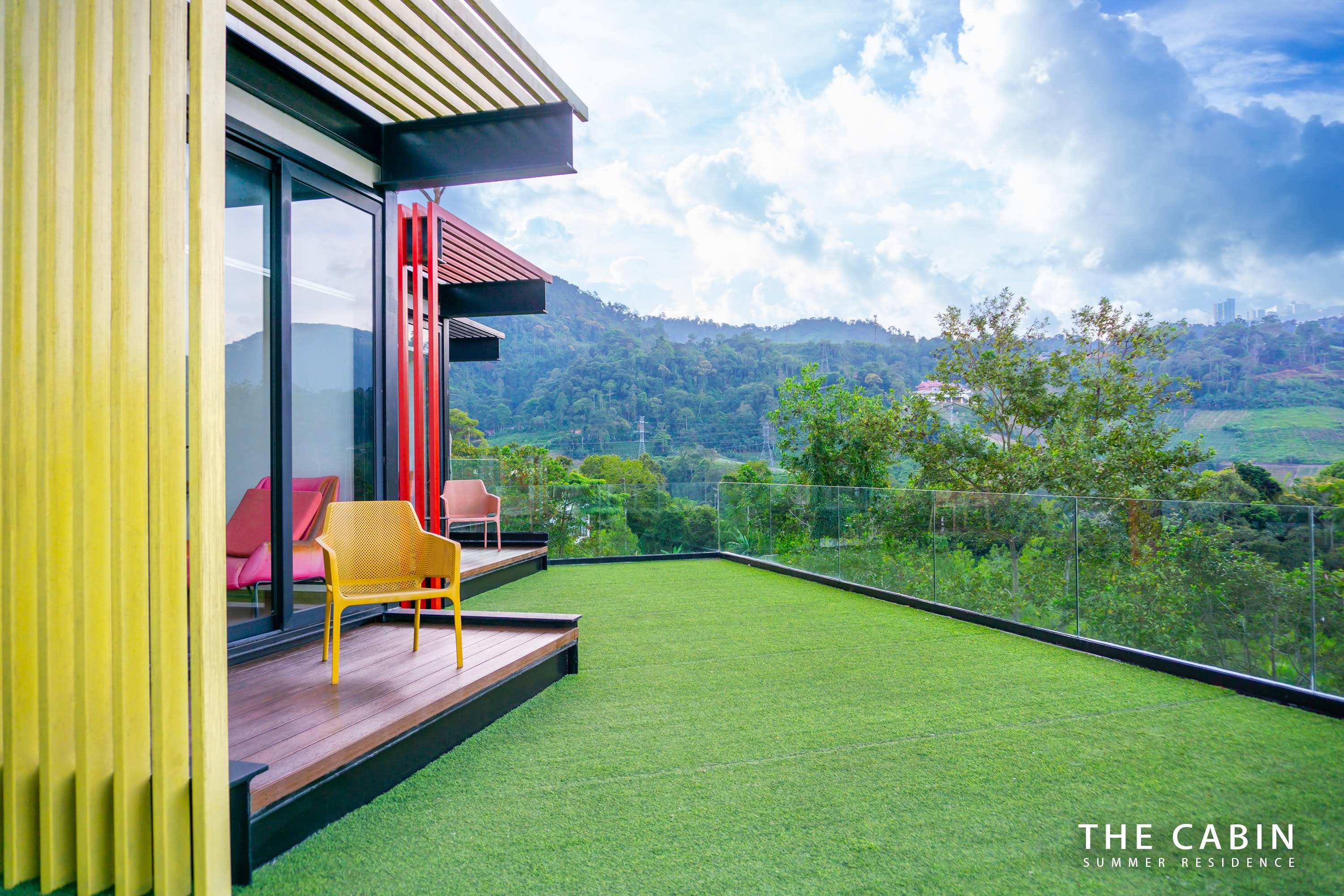 A cabin module clad in yellow slats, its balcony chairs and turfed roof terrace above the valley.