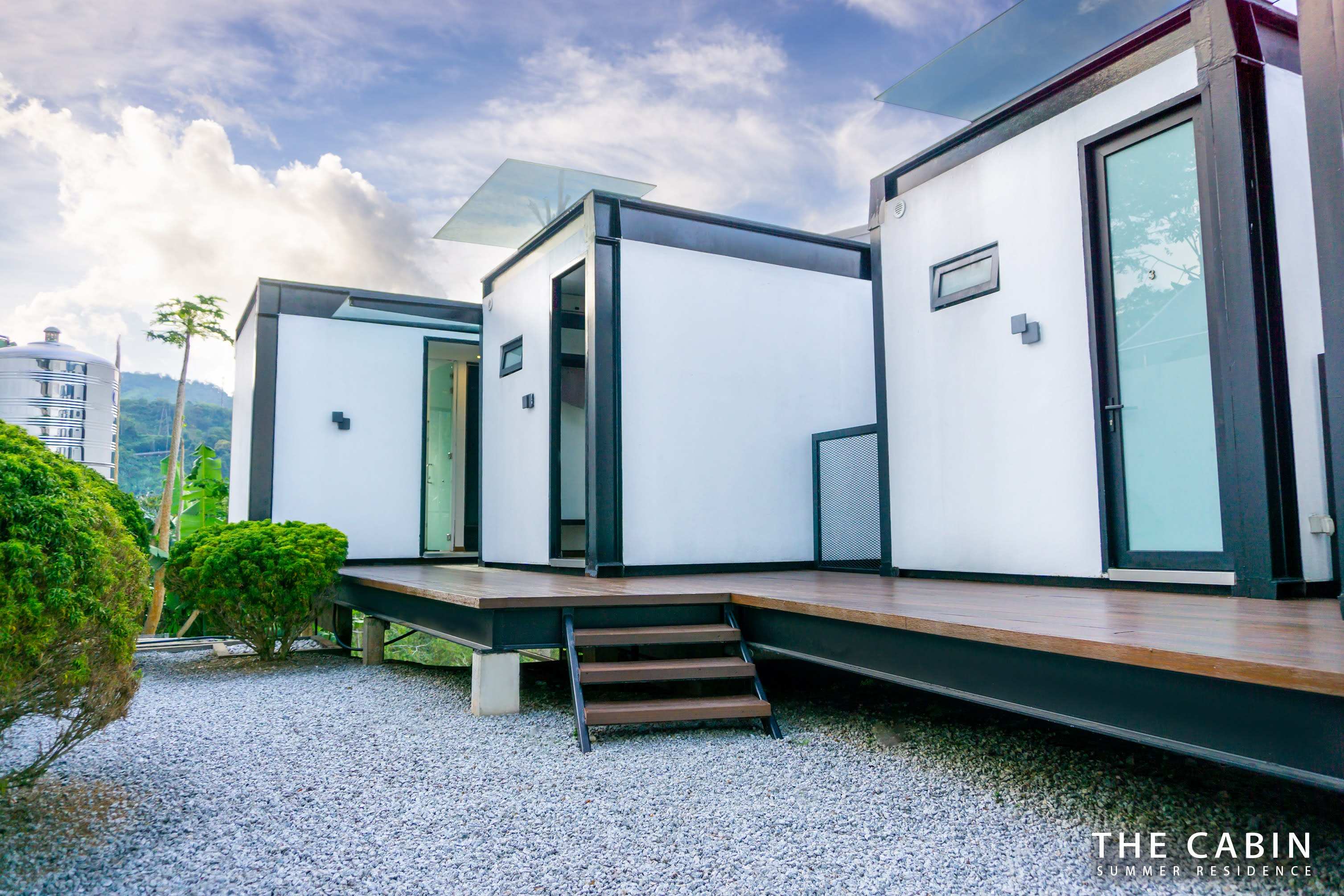 The stilted cabin units along the gravel path, greenery to one side.